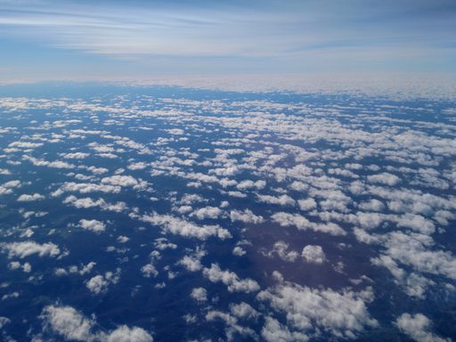 view from airplane window of small white clouds