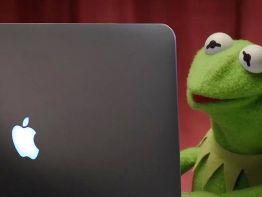 kermit the frog looks at screen of Mac laptop