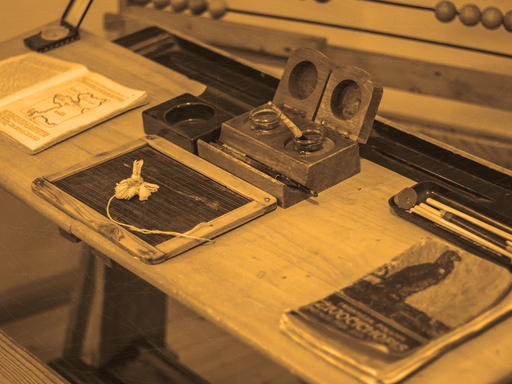 19th Century school desk with books, slate, pens, inkwells and pencils.