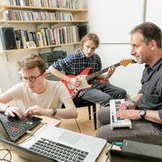 Two students and a professor compose music in an office
