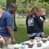 Empty Bowls 2019 attendees choose their bowls. Several individuals peruse a long table featuring many hand made clay bowls.