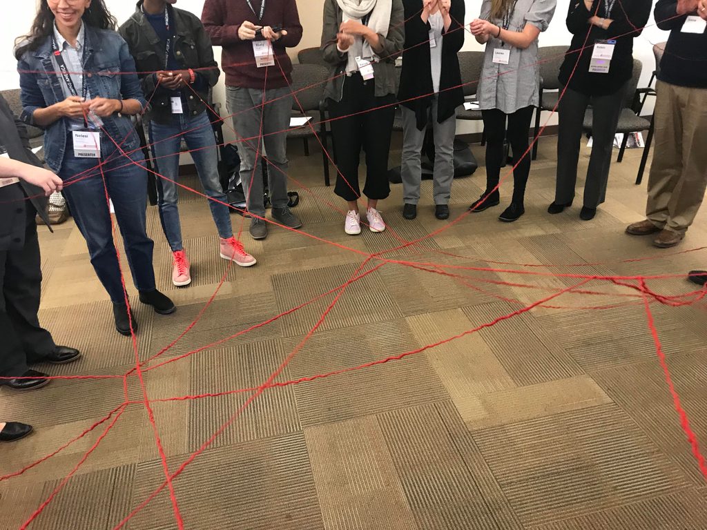 A "Web of Learning" at Professor Anita Chikkatur's Workshop. Participants stand in a circle, a web of string connecting them