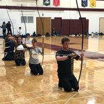 Kyudo Practice. Kyudo learners kneeling in a line with longbows.