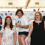 Five people standing in front of the olympics flag photo prop