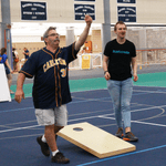 Two staff members are playing corn hole