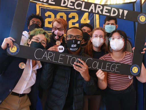 Eight people stand under a blue and yellow Class of 2024 banner, holding a sign to celebrate having declared their majors