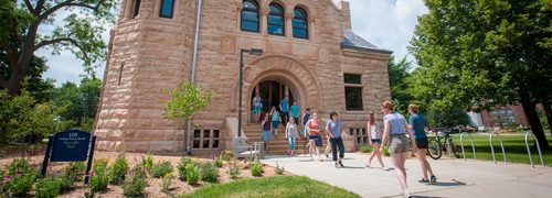 A campus tour group heading out of Scoville Hall on a sunny day