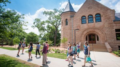 A student-led tour group leaves Admissions, most people in short sleeves