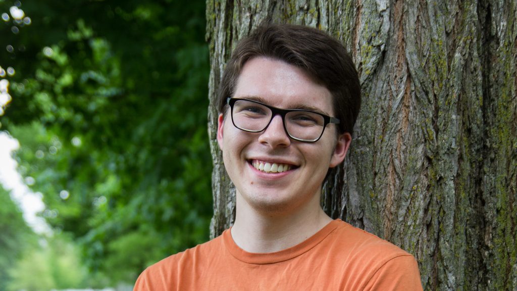 Gus Leinbach leans against a tree near the Bald Spot, Carleton's campus quad