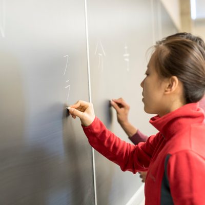 A student writes at the board in a Japanese class