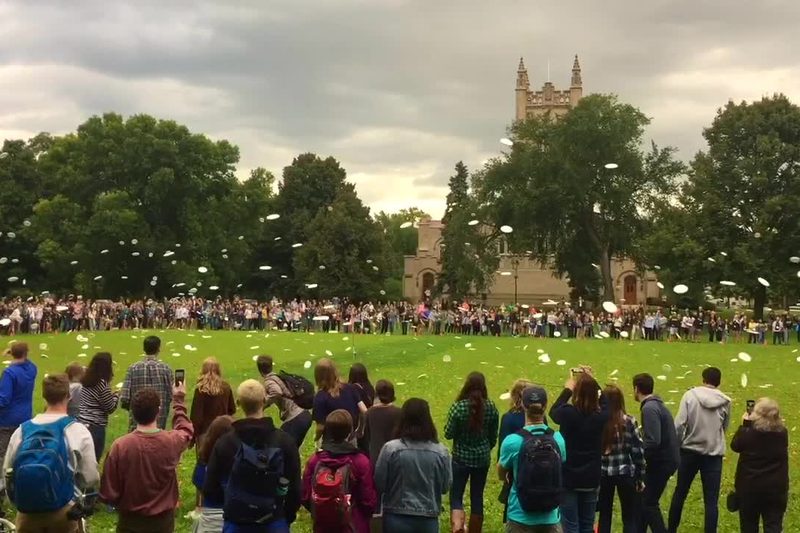 Students in a large circle throwing frisbees into the center of the circle
