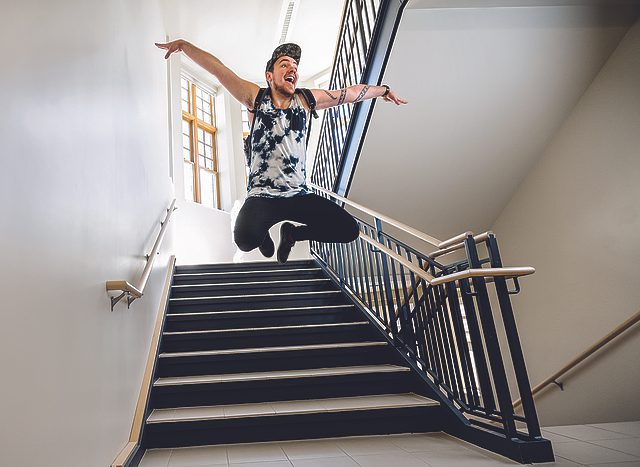 ​Mike Bahn in midair, arms extended, as he leaps in a dorm stairwell