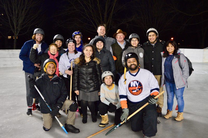 Students and staff pose on the ice in broomball attire.