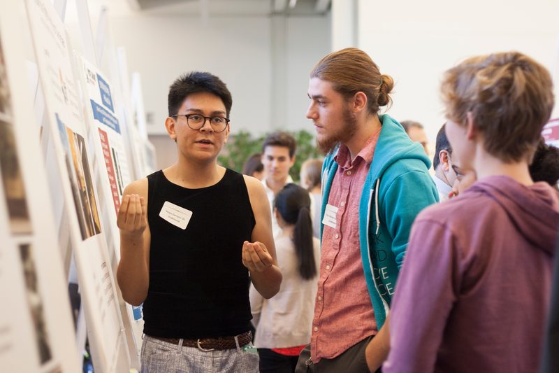 <p>Students have a conversation during a poster session for student research and externship positions</p>