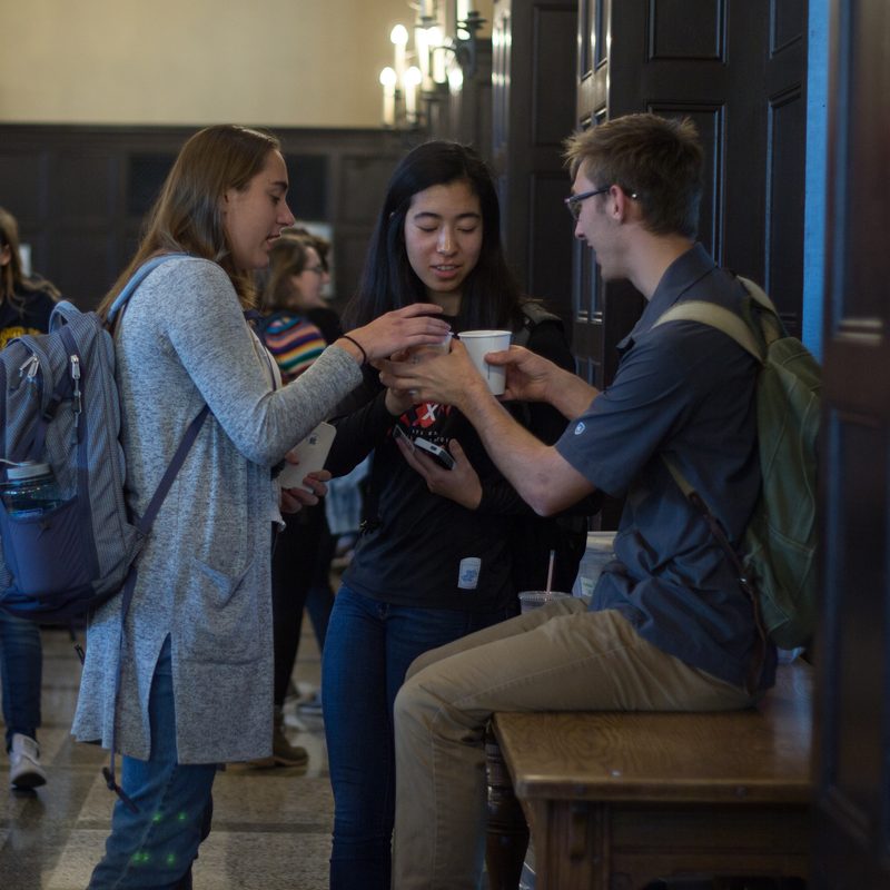 Three students chat in Carleton's wood-paneled Great Hall
