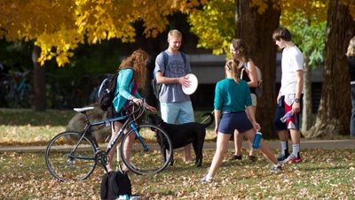 Students gather in between classes to throw a Frisbee on a fall day.