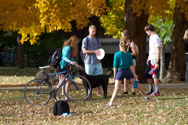Students gather in between classes to throw a Frisbee on a fall day.