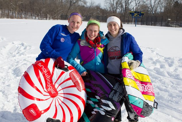 A group of Carleton students smile triumphantly after a long sledding session.
