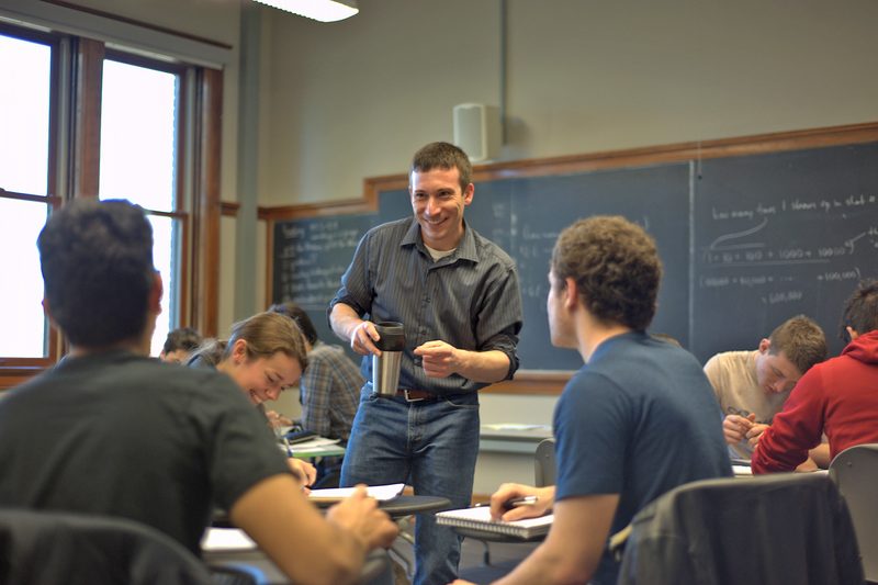A professor stands in front of students during a class discussion