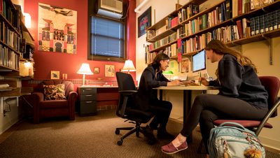 A professor and a student laugh together in an office