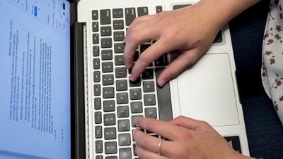 aerial view of a student's hands typing on a laptop