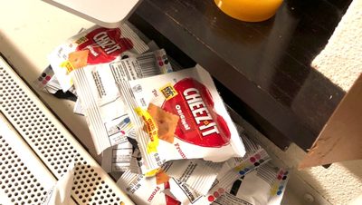 Picture of a computer on a desk with a glass of orange juice and many empty cheez it wrappers