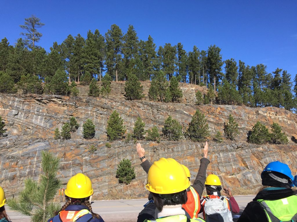 people in hardhats at roadside rocks
