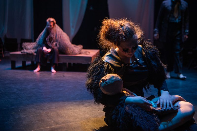 An actor cradling a doll in the Theater and Dance Department's production of That Wilderness of Glass