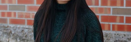 A student, Chloe Jones, smiling at the camera in front of a red brick wall