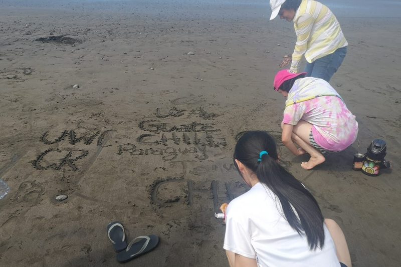 My high school friends and I writing our countries' names in the sand at the beach.