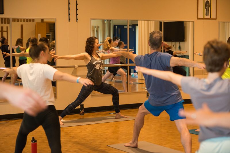 Yoga instructor leading class through warrior ii