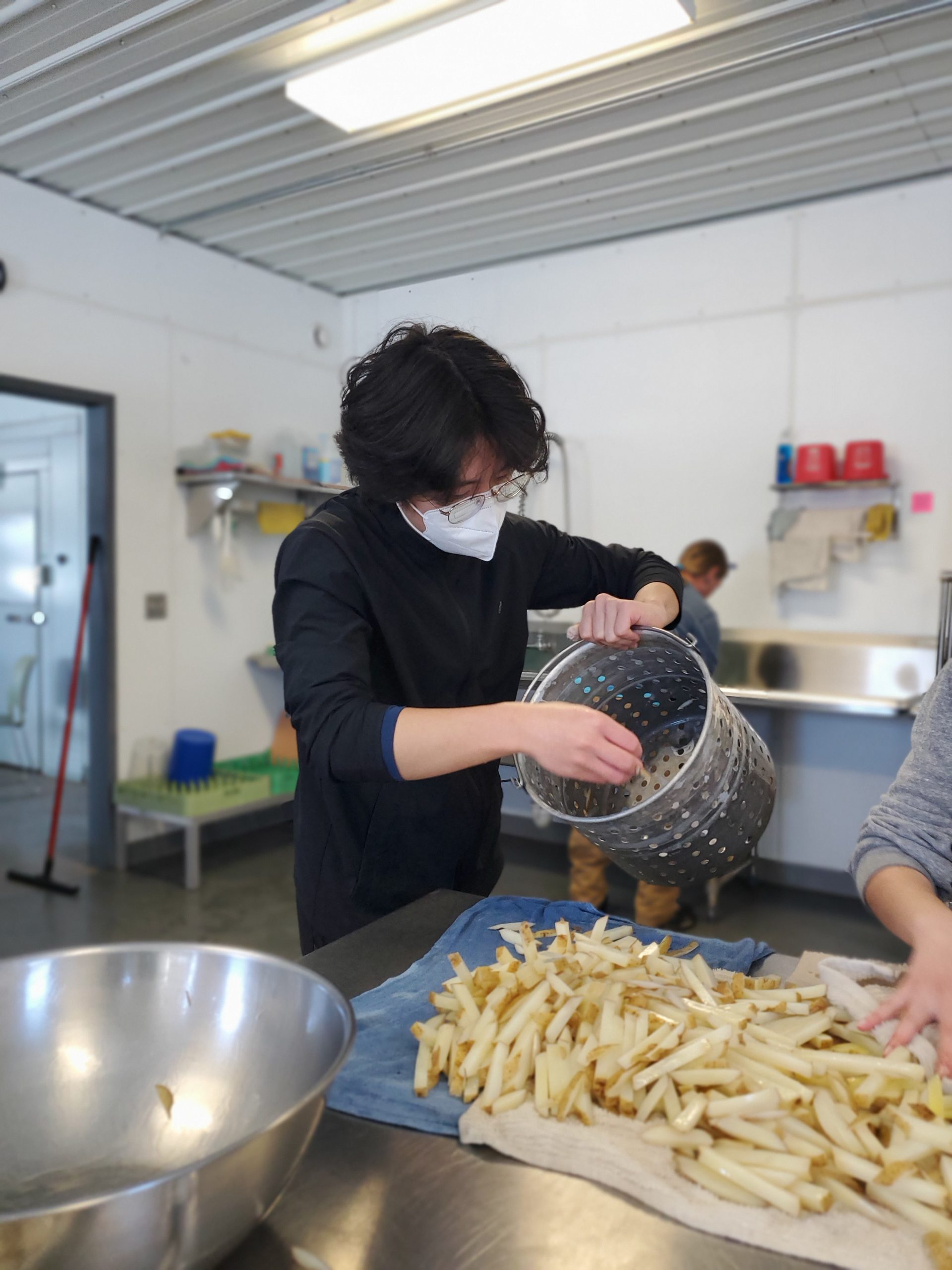 Bryan scoops French fries onto the table to be dried and oiled.