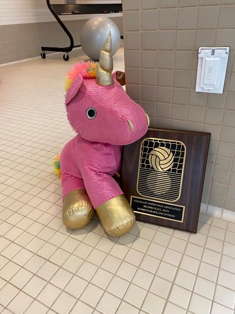 Our mascot Roxanne the Unicorn hugs the plaque