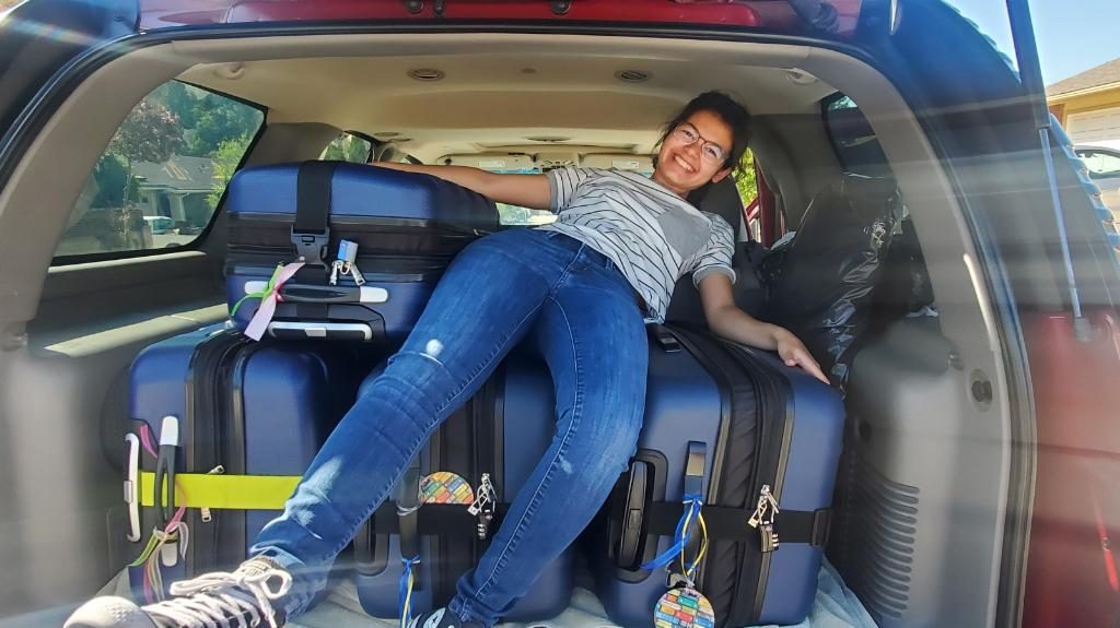 Lexi sits on top of her suitcases