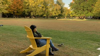 Student sits on the Bald Spot with fall leaves