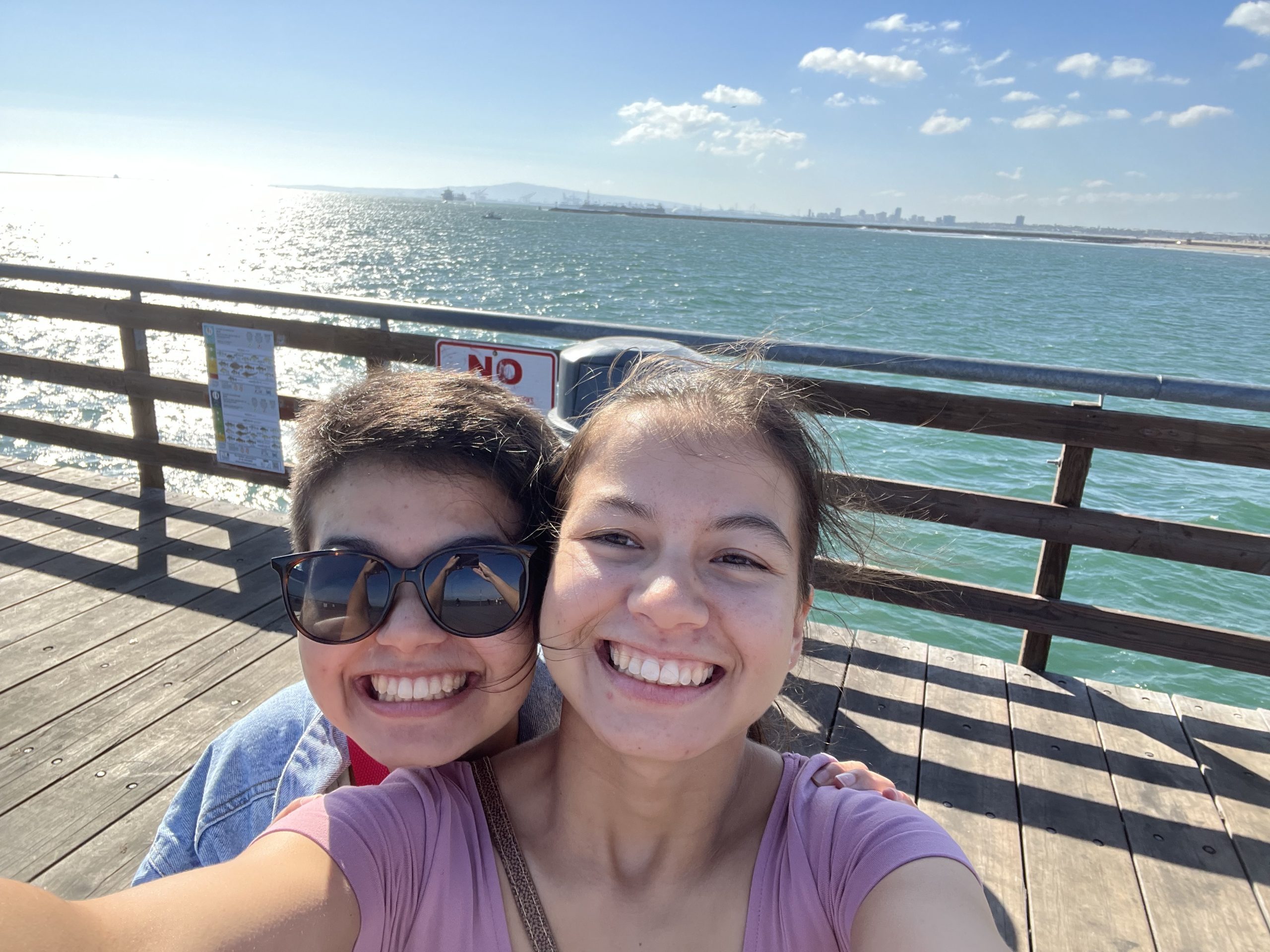 Two sisters smile on the pier