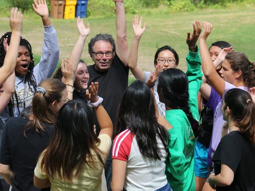 Students and teacher with their hands in the air
