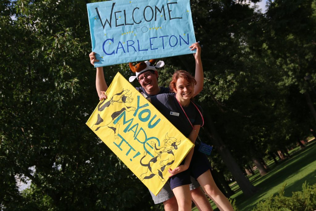 Two PACAs holding up Carleton welcome signs