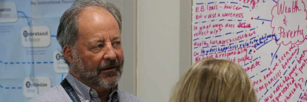 APSI Consultant Talking with participant with a "wealth and poverty" bubble diagram in the background