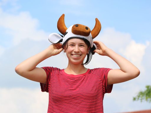 Student holding a cow hat on their head and smiling