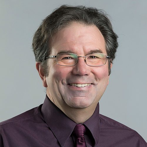 Headshot of Professor Larry Wichlinski from the shoulders up. He is smiling and wearing glasses with a maroon button up shirt and tie.
