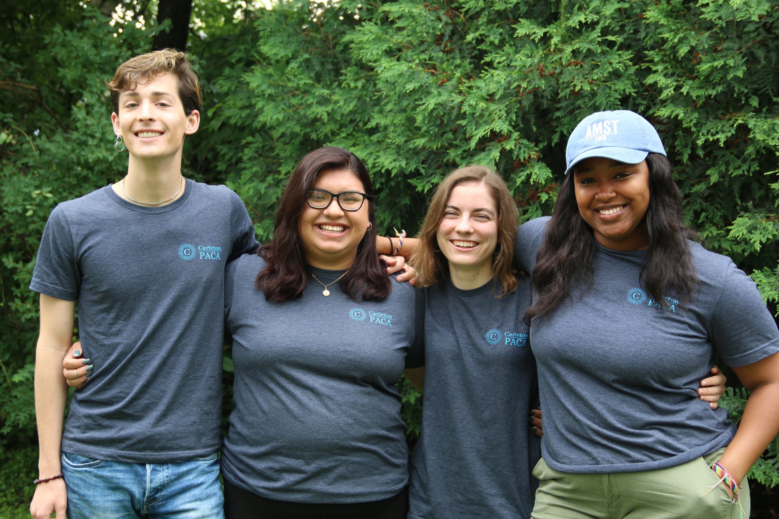 Four Program and Community Assistants wearing grey staff shirts and smiling