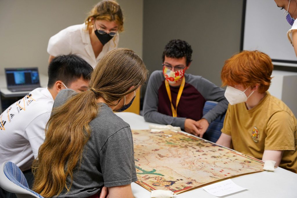 Humanities students lean over a map