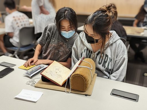 Two students look at an archival map book