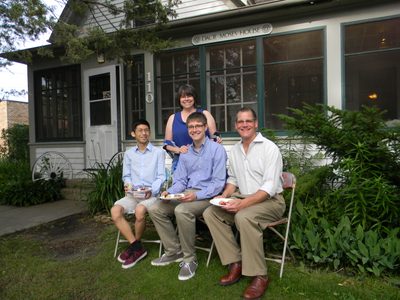 Four people pose for a photo in front of a house