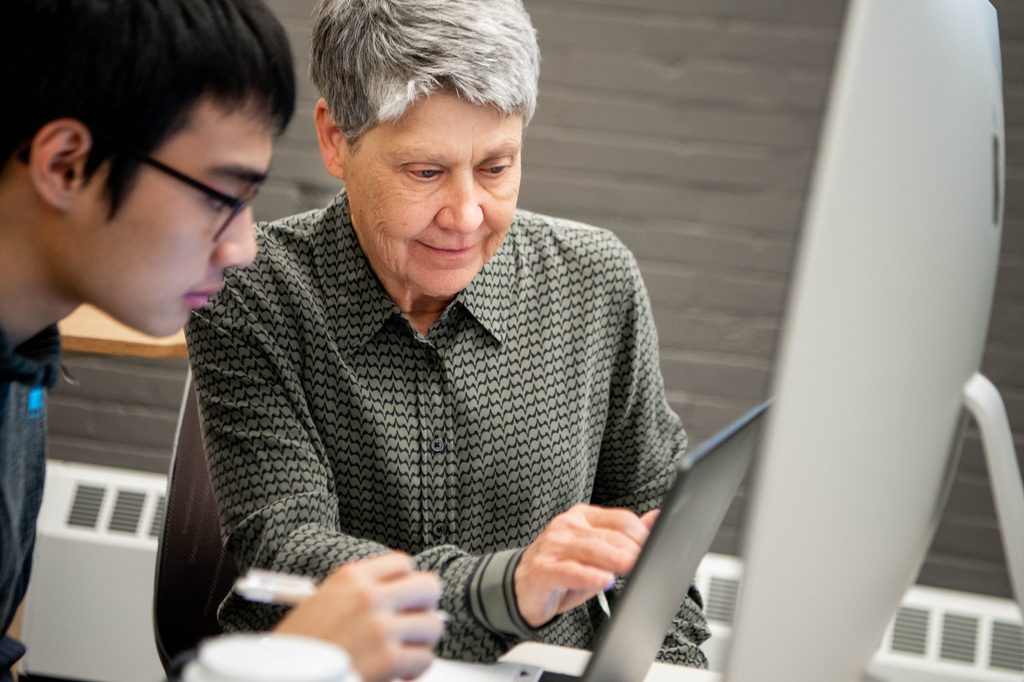 Student and professor look at a computer screen