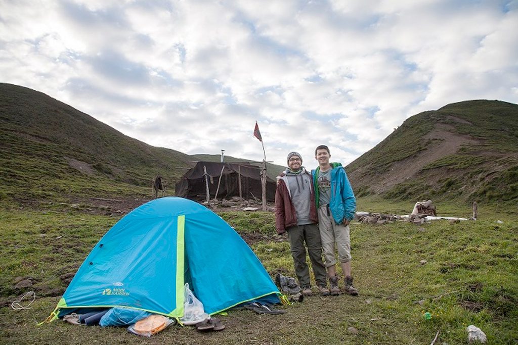 two students stand besde a tent