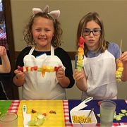 Four kids assembling food in a kitchen