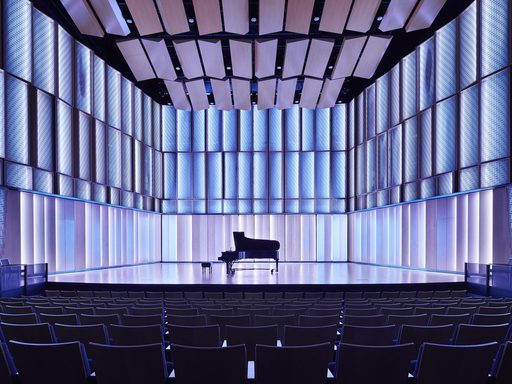 View of the Kracum Performance Hall stage with blue back lighting and a piano at center stage