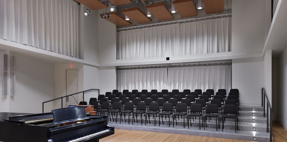 Applebaum Recital Hall, a choir rehearsal space, with piano, risers, and chairs.